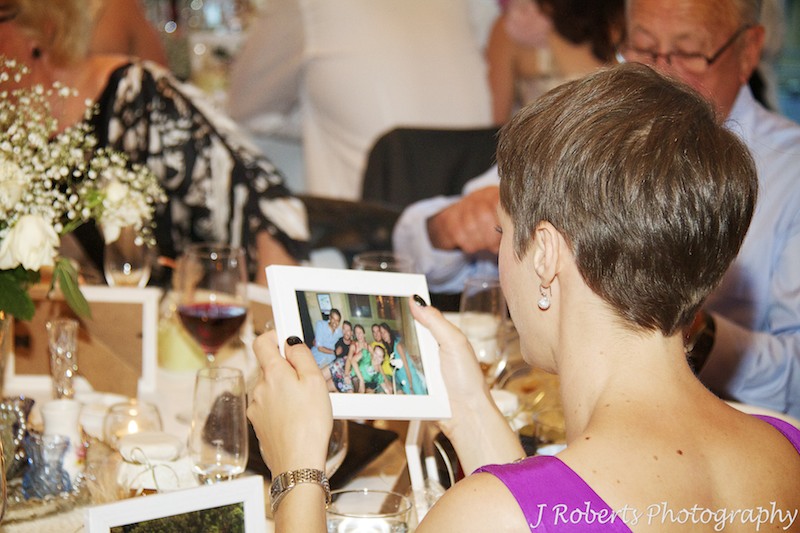 Guests studying photos of themselves at wedding reception - wedding photography sydney